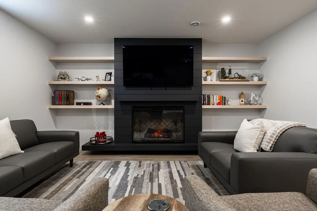 axium-interiors-saskatoon-fireplace-basement-floating-shelves-DSC08281-HDR Walkout basement with dark cabinetry and gold accents, bright and spacious with floor to ceiling windows